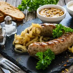 Pyszna biała kiełbasa pieczona w cebuli i musztardzie, podana z chlebem i sosami.