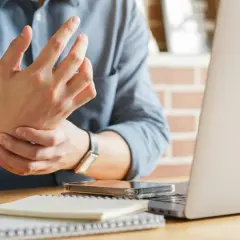 Uomo con male ai polsi mentre lavora al computer. Dolore al polso da uso prolungato del mouse e tastiera.