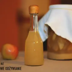 Butelka z octem jabłkowym, obok jabłko i słoik z fermentującymi jabłkami. Czy ocet jabłkowy zawiera alkohol?