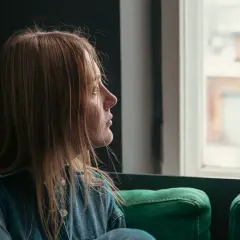 En kvinna med utmattning tittar ut genom fönstret, drömmer om att bli frisk.