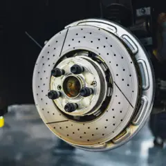 Disque de frein perforé et ventilé, prêt à arrêter la voiture. Ce frein qui siffle pourrait indiquer un besoin de maintenance.