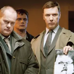 Mikael Persbrandt i en scen från filmer och tv-program. Han håller upp ett fotografi av en man.