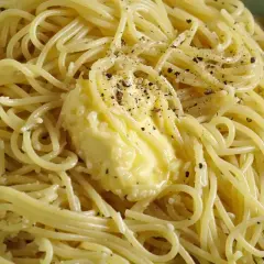 Spaghetti fumanti con burro fuso e pepe nero macinato, pronti per la cacio e pepe ricetta originale romana.
