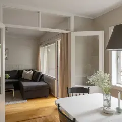 Jasne, oto opis:

Nowoczesne wnętrze z szarą kanapą i białym stołem. W tle widoczne są subtelne **wzory geometryczne** na ścianie, dodające elegancji.