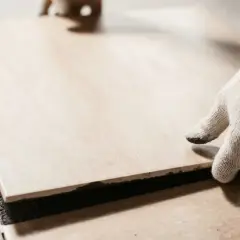 A gloved hand places a tile. Walking on tile too soon can cause shifting and unevenness.