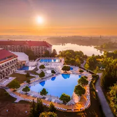Widok z lotu ptaka na hotel z basenami i jeziorem o wschodzie słońca.