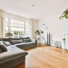 Gemütliches kleines Wohnzimmer einrichten mit großem Ecksofa, Bogenlampe, Pflanzen und mintgrünem Schrank.