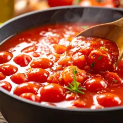 Heiß dampfende Tomatensoße mit ganzen Kirschtomaten, perfekt für Pasta. Ein Hauch von Rosmarin und ein Löffel voller Genuss.