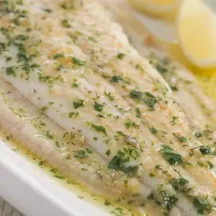 Sogliola alla mugnaia succulenta, cosparsa di prezzemolo fresco e servita con spicchi di limone.