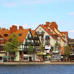 Urokliwa nadmorska promenada z kolorowymi kamieniczkami, jak z bajki o Mikołajkach w Warszawie.