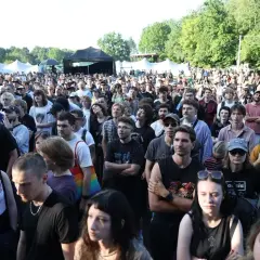 Tłum ludzi na koncercie w Katowicach. Słońce, drzewa i namioty festiwalowe w tle. Atmosfera festiwalu Katowice Off Festival.