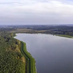 Rozległy zalew Biszcza otoczony lasem i zielonymi łąkami. Spokojna tafla wody odbija niebo.