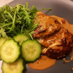 Kyckling i krämig sås med sambal oelek, serverad med ruccola och gurkskivor.