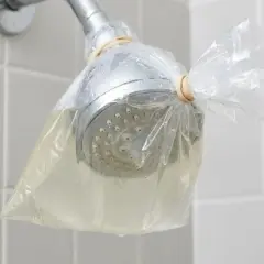 Doccia con soffione avvolto in un sacchetto pieno di liquido, per rimuovere residui di autoabbronzante che si toglie con l'acqua.