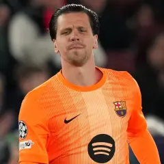 Bramkarz w pomarańczowej koszulce FC Barcelona, z herbem klubu na piersi. To właśnie w tym klubie gra Szczęsny.