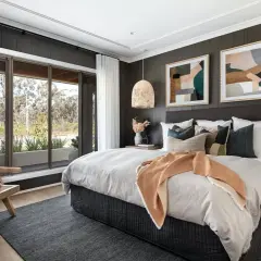 Light wood nightstands complement the dark wood bed. A cozy bedroom with a large window, rattan chair, and abstract art.