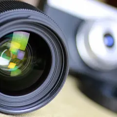Obiektyw aparatu z widocznymi odbiciami, gotowy do uchwycenia wyjątkowych chwil. To symbol akredytacji fotograficznej.