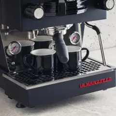 Profesjonalny ekspres do kawy La Marzocco z dwoma czarnymi filiżankami. Dowiedz się, jak odpowietrzyć ekspres Delonghi, by cieszyć się idealnym espresso.