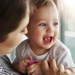 Bambino sorridente con la mamma, forse è l'inizio della lallazione.
