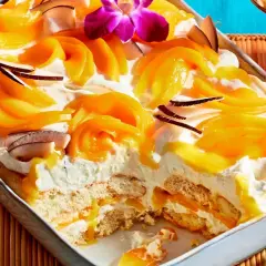 Ein cremiges Mango Tiramisu mit Kokosflocken und einer exotischen Orchidee verziert.