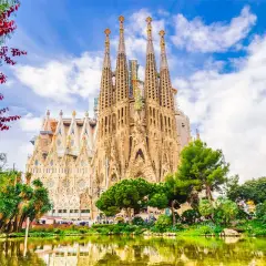 Sagrada Familia, z jej unikalną architekturą i otaczającą zielenią, to miejsce pełne ciekawostek. Woda w stawie odbija majestatyczne wieże.