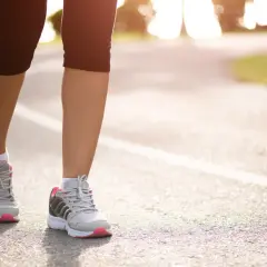 Kobieta w sportowych butach biegnie po asfalcie. Czy bieganie odchudza? Tak, regularny wysiłek fizyczny pomaga spalać kalorie i kształtować sylwetkę.