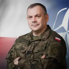 Generał Rajmund Andrzejczak, szef sztabu generalnego wojska polskiego, na tle flagi Polski i NATO.