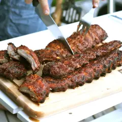 Grillade kamben skärs upp på en skärbräda. Saftiga och rökiga, redo att avnjutas.