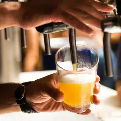 Ręka nalewa piwo do szklanki. Może to być pierwszy krok do tego, jak zrobić tort z piw.