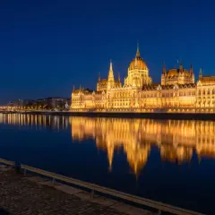 Wspaniały budynek Parlamentu w Budapeszcie odbija się w spokojnej rzece o zmierzchu.