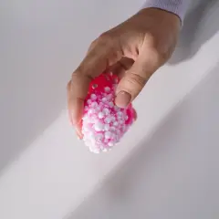 Dłoń trzyma różowy slime z kulkami, który wygląda jak mała, puszysta chmurka.