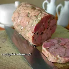 Gotowy do krojenia szynkowar, idealny do domowych przepisów. Obok leży plasterek, a nóż czeka na dalsze porcje.