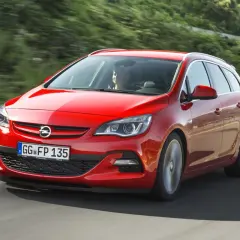 Czerwona Astra J 1.7 CDTI w wersji kombi pędzi po krętej drodze wśród zieleni.