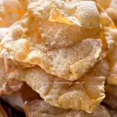 Chiacchiere croccanti, una deliziosa chiacchiere ricetta della nonna, cosparse di zucchero a velo.