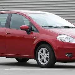 Czerwony Fiat Punto Grande z tablicą rejestracyjną SB 2823E zaparkowany na szarym podłożu.