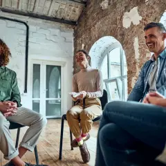 Ludzie siedzą w kręgu, śmiejąc się. Terapia grupowa nie dla wszystkich, ale dla nich to chwila radości i wsparcia.
