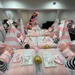 Urocze namioty tipi w różowo-białe paski, poduszki z Wieżą Eiffla i balony tworzą magiczne **pomysły na nocowanie** dla dziewczynek.
