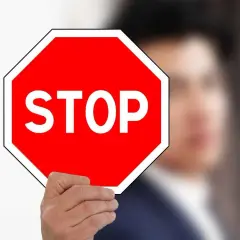 Mężczyzna trzyma czerwony znak stop.