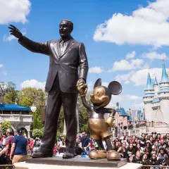 Walt Disney i Myszka Miki pozdrawiają tłumy przed zamkiem w największym Disneylandzie na świecie.