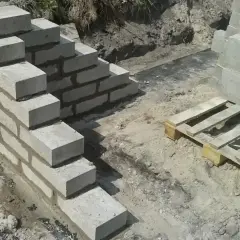 Budowa schodów z bloczków betonowych, gdzie zaprawa murarska do bloczków betonowych spaja kolejne warstwy.