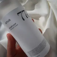 Anua Heartleaf Soothing Toner 77% w dłoni na tle białej tkaniny. Idealny do codziennej pielęgnacji.