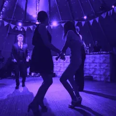 Tańczący ludzie na weselu przy świetle fioletowych lamp. Idealna playlista na wesele sprawia, że wszyscy bawią się świetnie.