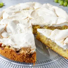 Ein saftiger omas stachelbeerkuchen mit luftiger Baiserhaube auf einem Tortenteller.