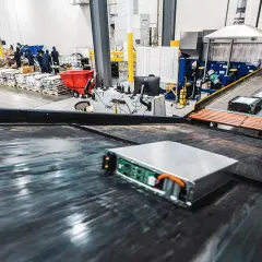 Proces utylizacji baterii samochodów elektrycznych. Baterie na taśmie produkcyjnej, pracownicy w tle.