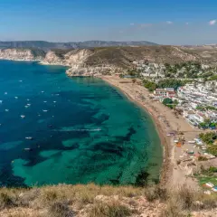 Vista aérea de la costa con aguas turquesas, barcos y el pueblo blanco de restaurante costamarga.