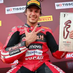 Nicolò Bulega, piloto de Ducati, celebra su victoria en Motorland Aragón con el trofeo y haciendo la señal de la victoria.