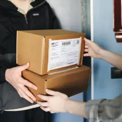Dwie osoby przekazują sobie paczki. Na jednej z nich widoczna jest etykieta z kodem kreskowym. Ile cyfr ma kod nadania InPost?