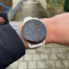 Biały zegarek Garmin na nadgarstku, z widocznym tętnem i liczbą kroków.