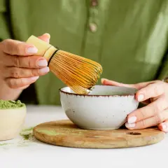 Przygotowanie najlepszej zielonej herbaty matcha. W drewnianej miseczce proszek, w ceramicznej miseczce napar, ubijany bambusowym miotełką.