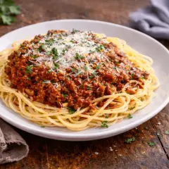 Pyszne spaghetti bolognese, idealne na prosty przepis. Danie posypane parmezanem i natką pietruszki.